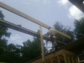 Carpenter setting a ridge beam over a new addition frame — Ice Dam Removal by Roofing Brothers in Abilene