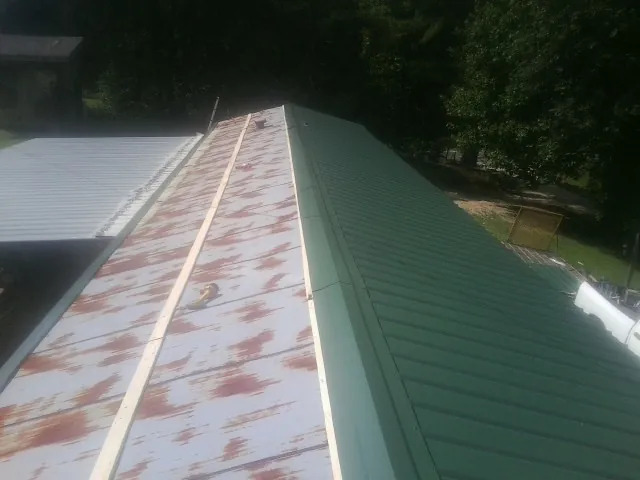 Old rusted panels beside newly installed green metal roofing — Wind Damage Roof Repair by Roofing Brothers in Abilene