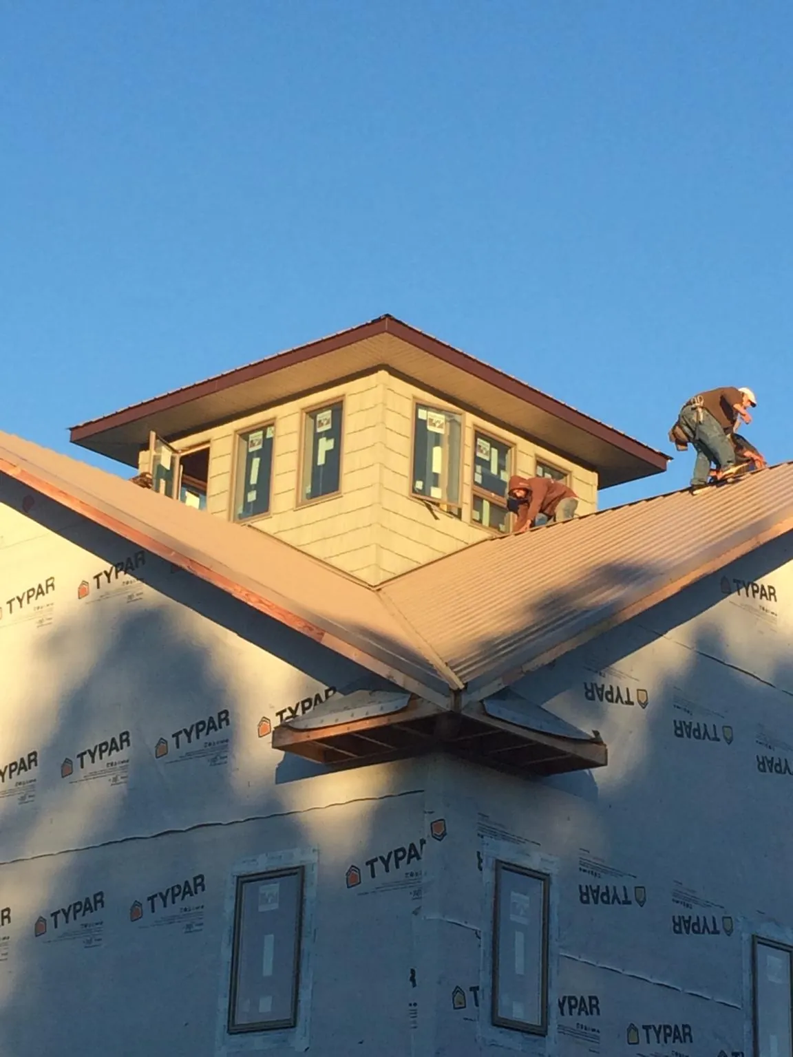 Roofers working around a rooftop cupola on a new metal roof at sunset — Roof Waterproofing in Abilene by Roofing Brothers